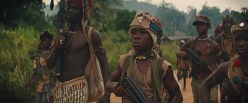 Movie still from “Beasts of No Nation” (2015), directed by Cary Joji Fukunaga – Two men in native dress are standing in the grass; Medium shot, Low angle