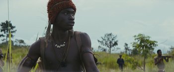 Movie still from “Beasts of No Nation” (2015), directed by Cary Joji Fukunaga – A man with a red hat is standing in the grass; Close Up shot, Low angle