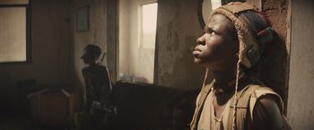 Movie still from “Beasts of No Nation” (2015), directed by Cary Joji Fukunaga – A man standing in a living room looking up at the ceiling; Close Up shot, Low angle