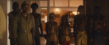 Movie still from “Beasts of No Nation” (2015), directed by Cary Joji Fukunaga – A group of people standing next to each other in a room; Medium shot, Low angle