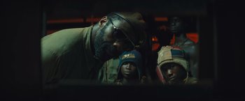 Movie still from “Beasts of No Nation” (2015), directed by Cary Joji Fukunaga – A group of men standing next to each other in a room; Close Up shot, Low angle