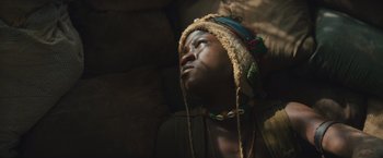 Movie still from “Beasts of No Nation” (2015), directed by Cary Joji Fukunaga – A young boy wearing a hat and a necklace looks upward; Close Up shot, Low angle