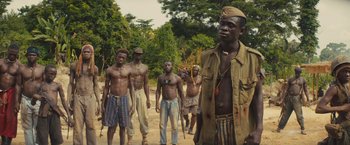 Movie still from “Beasts of No Nation” (2015), directed by Cary Joji Fukunaga – A group of men standing on top of a dirt road; Medium shot, Low angle