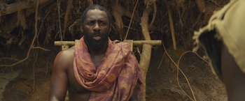 Movie still from “Beasts of No Nation” (2015), directed by Cary Joji Fukunaga – A man with a beard wearing a scarf and sitting in a chair; Close Up shot, Low angle