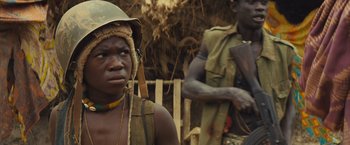 Movie still from “Beasts of No Nation” (2015), directed by Cary Joji Fukunaga – A man in a hat is standing next to another man; Close Up shot, High angle
