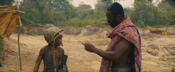 Movie still from “Beasts of No Nation” (2015), directed by Cary Joji Fukunaga – A man talking to a woman on the side of a dirt road; Medium shot, Over the shoulder angle