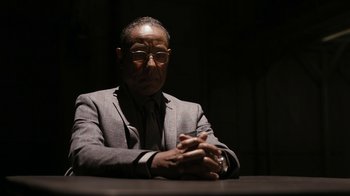 Movie still from “Better Call Saul” (2015), created by Vince Gilligan – An older man sitting at a table with his hands crossed; Close Up shot, Low angle