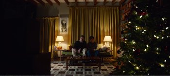 Movie still from “Black Mirror: Bandersnatch” (2018), directed by David Slade – Two people sitting on a couch in a living room; Wide shot, Low angle