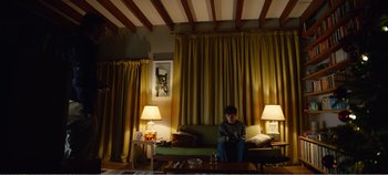 Movie still from “Black Mirror: Bandersnatch” (2018), directed by David Slade – A person sitting on a couch in a living room; Wide shot, Low angle