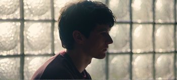 Movie still from “Black Mirror: Bandersnatch” (2018), directed by David Slade – A young man looking out of a window at the sun; Close Up shot, Over the shoulder angle