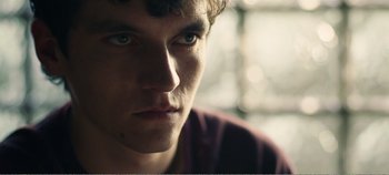 Movie still from “Black Mirror: Bandersnatch” (2018), directed by David Slade – A young man's face; Close Up shot, Over the shoulder angle