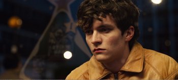 Movie still from “Black Mirror: Bandersnatch” (2018), directed by David Slade – A young man in a yellow jacket looking to his left; Close Up shot, High angle