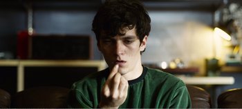 Movie still from “Black Mirror: Bandersnatch” (2018), directed by David Slade – A young man is holding his finger to his mouth; Close Up shot, High angle