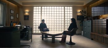 Movie still from “Black Mirror: Bandersnatch” (2018), directed by David Slade – Two people sitting at a table in front of a large window; Wide shot, Over the shoulder angle