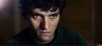 Movie still from “Black Mirror: Bandersnatch” (2018), directed by David Slade – A man's face with blue eyes; Close Up shot, Low angle