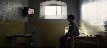 Movie still from “Black Mirror: Bandersnatch” (2018), directed by David Slade – A man sitting on a chair in front of a television; Wide shot, Over the shoulder angle