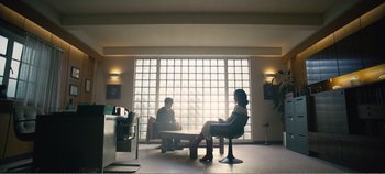 Movie still from “Black Mirror: Bandersnatch” (2018), directed by David Slade – Two people sitting on a bench in front of a window; Wide shot, Low angle