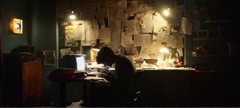 Movie still from “Black Mirror: Bandersnatch” (2018), directed by David Slade – A man sitting at a desk in front of a computer; Wide shot, Low angle