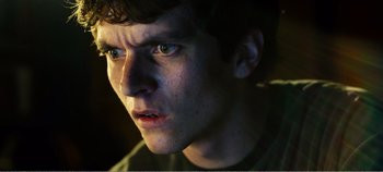 Movie still from “Black Mirror: Bandersnatch” (2018), directed by David Slade – A young man's face in the dark; Close Up shot, Low angle