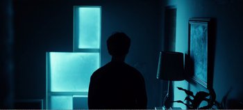 Movie still from “Black Mirror: Bandersnatch” (2018), directed by David Slade – A man standing in front of a window at night; Medium shot, Low angle