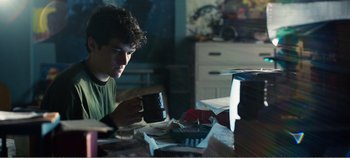 Movie still from “Black Mirror: Bandersnatch” (2018), directed by David Slade – A man sitting at a table drinking a cup of coffee; Medium shot, Over the shoulder angle