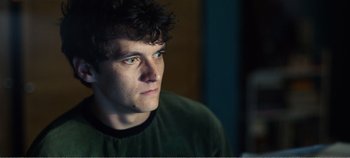 Movie still from “Black Mirror: Bandersnatch” (2018), directed by David Slade – A young man looking into the distance while sitting in a room; Close Up shot, Low angle