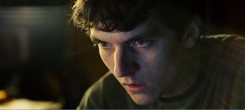 Movie still from “Black Mirror: Bandersnatch” (2018), directed by David Slade – A young man's face in the dark; Close Up shot, Low angle