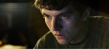 Movie still from “Black Mirror: Bandersnatch” (2018), directed by David Slade – A young man's face in the dark; Close Up shot, Low angle