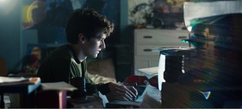 Movie still from “Black Mirror: Bandersnatch” (2018), directed by David Slade – A man sitting at a table using a computer; Medium shot, Low angle
