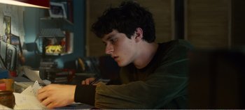 Movie still from “Black Mirror: Bandersnatch” (2018), directed by David Slade – A man sitting at a table writing on a piece of paper; Medium shot, Over the shoulder angle