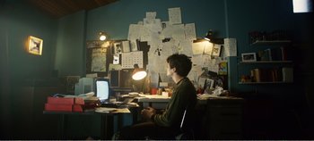 Movie still from “Black Mirror: Bandersnatch” (2018), directed by David Slade – A man sitting at a desk in front of a computer; Wide shot, High angle