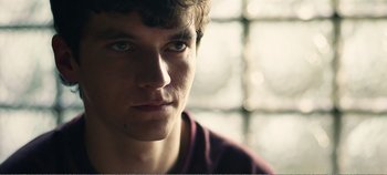 Movie still from “Black Mirror: Bandersnatch” (2018), directed by David Slade – A young man's face in front of a window; Close Up shot, Over the shoulder angle