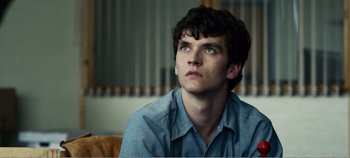 Movie still from “Black Mirror: Bandersnatch” (2018), directed by David Slade – A man sitting on a couch looking up at the sky; Close Up shot, Low angle