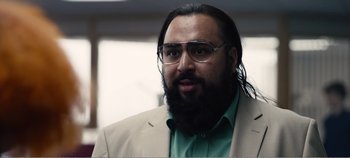 Movie still from “Black Mirror: Bandersnatch” (2018), directed by David Slade – A man with a beard wearing glasses and a suit; Close Up shot, Over the shoulder angle