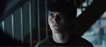Movie still from “Black Mirror: Bandersnatch” (2018), directed by David Slade – A young man stares into the distance in a dark room; Close Up shot, Low angle