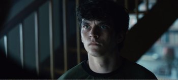 Movie still from “Black Mirror: Bandersnatch” (2018), directed by David Slade – A young man with blue eyes stares into the distance; Close Up shot, Low angle