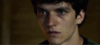 Movie still from “Black Mirror: Bandersnatch” (2018), directed by David Slade – A young man's face with green eyes; Close Up shot, Over the shoulder angle