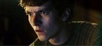Movie still from “Black Mirror: Bandersnatch” (2018), directed by David Slade – A young man's face in the dark; Close Up shot, Low angle