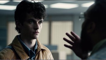 Movie still from “Black Mirror: Bandersnatch” (2018), directed by David Slade – A man in a brown jacket talking to a woman in a brown jacket; Close Up shot, Over the shoulder angle