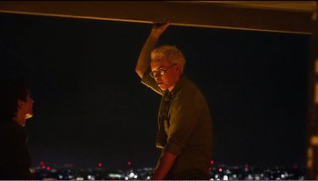 Movie still from “Black Mirror: Bandersnatch” (2018), directed by David Slade – A man standing on a balcony at night; Medium shot, Low angle
