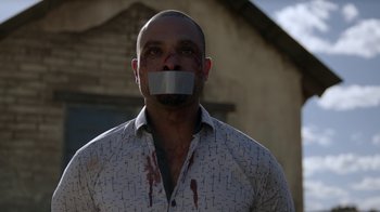 Movie still from “Better Call Saul” (2015), created by Vince Gilligan – A man with his mouth taped shut with blood on his face; Close Up shot, Low angle