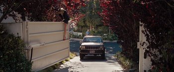 Movie still from “Bridesmaids” (2011), directed by Paul Feig – A woman standing on the side of a wall next to a jeep; Wide shot, Low angle