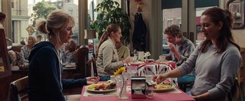 Movie still from “Bridesmaids” (2011), directed by Paul Feig – A group of people sitting at a table with plates of food on it; Medium shot, Over the shoulder angle