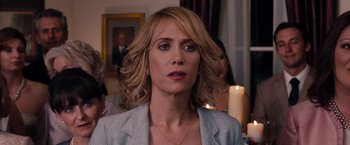 Movie still from “Bridesmaids” (2011), directed by Paul Feig – A person wearing a suit and a necklace; Close Up shot, Over the shoulder angle