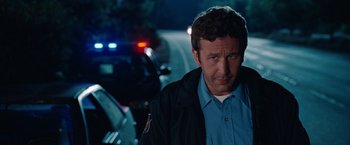 Movie still from “Bridesmaids” (2011), directed by Paul Feig – A man standing in front of a police car; Close Up shot, Over the shoulder angle