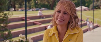 Movie still from “Bridesmaids” (2011), directed by Paul Feig – A woman in a yellow jacket smiling for the camera; Close Up shot, Over the shoulder angle