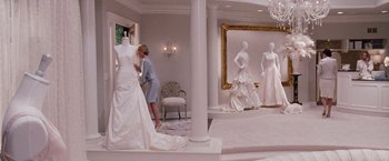 Movie still from “Bridesmaids” (2011), directed by Paul Feig – A woman in a white dress looking at some dresses; Wide shot, Over the shoulder angle
