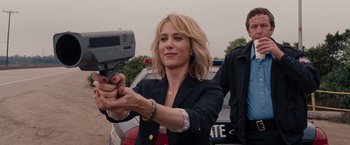 A woman holding a video camera in front of a police car