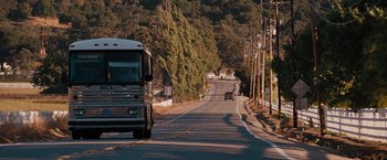 Movie still from “Bridesmaids” (2011), directed by Paul Feig – A bus driving down a street next to a forest; Extreme Wide shot, High angle