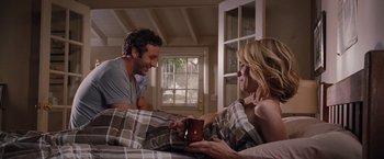 Movie still from “Bridesmaids” (2011), directed by Paul Feig – A man and a woman sitting on a bed with a cup; Medium shot, Over the shoulder angle